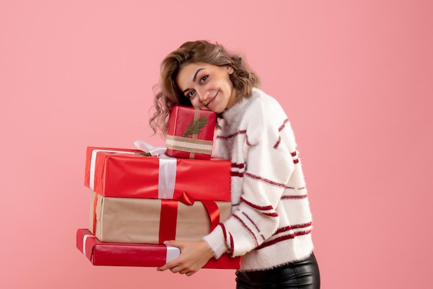 Вид спереди молодая женщина, держащая рождественские подарки
