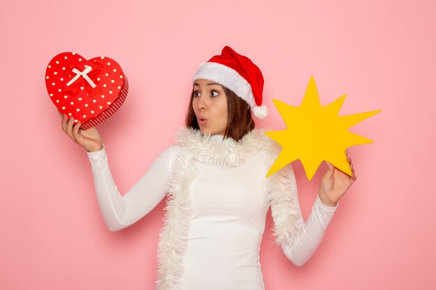 전면보기 젊은 여성 노란색 그림을 들고 분홍색 벽에 선물 크리스마스 색상 휴일 새해 패션