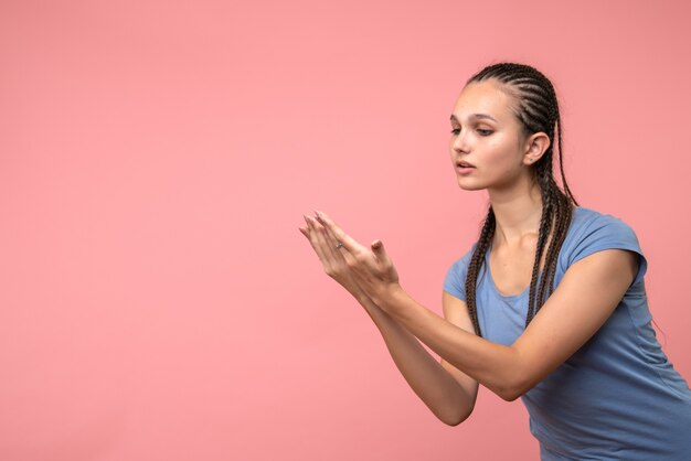 Front view of young female imitating reading on pink