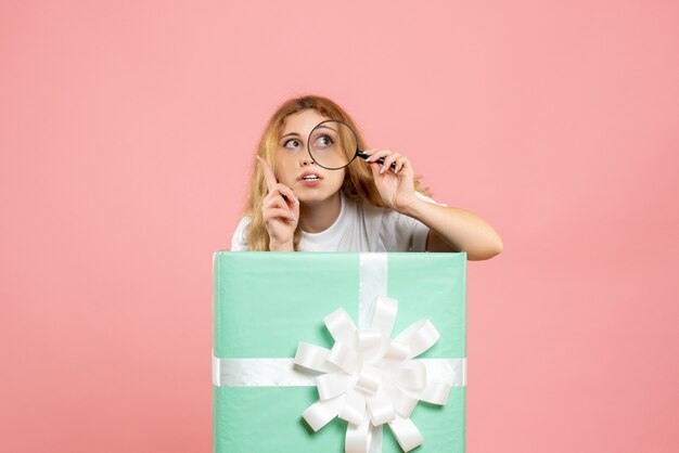 Front view young female inside blue present box using magnifier