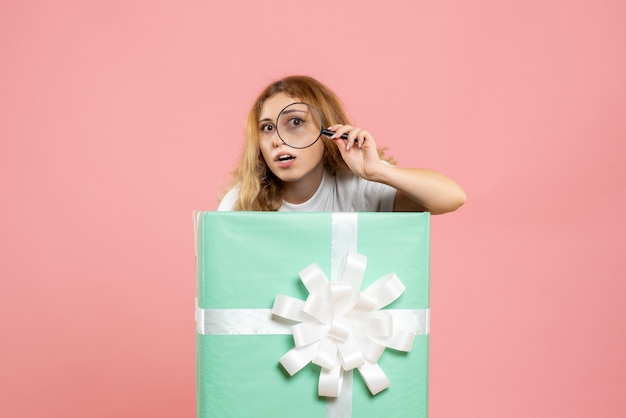 Front view young female inside blue present box using magnifier