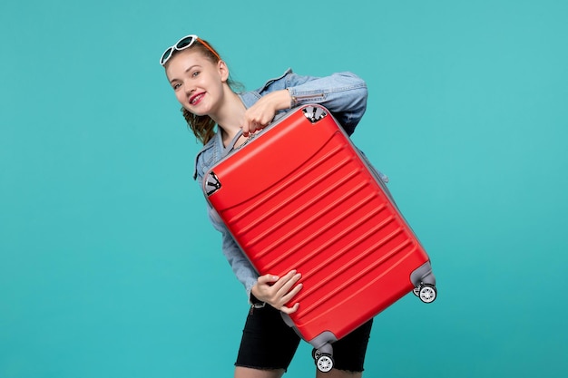 Free photo front view young female in jean jacket holding her red bag on light blue space