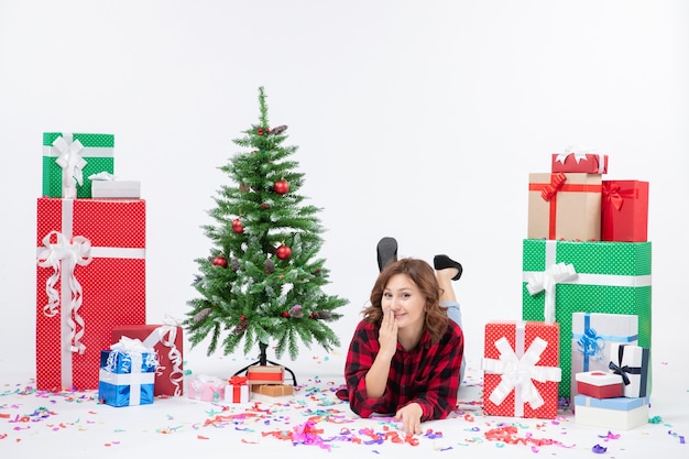 Vista frontale giovane femmina posa intorno a regali di natale e albero di vacanza su sfondo bianco natale capodanno regalo colore neve emozioni