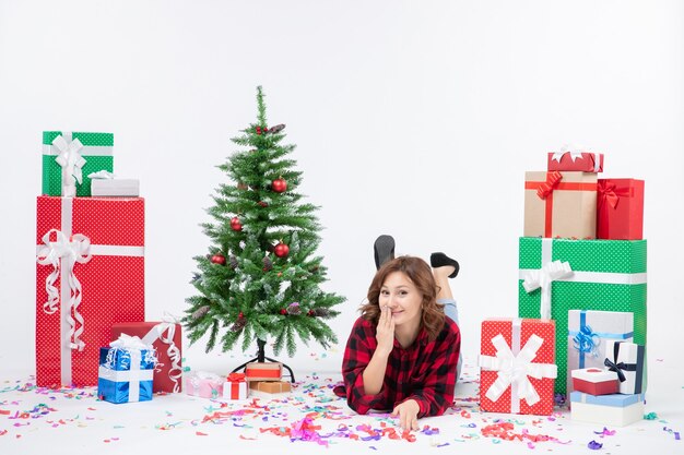 Front view young female laying around christmas presents and holiday tree on white background xmas new year gift color snow emotions