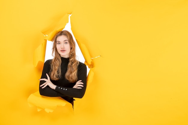 Free photo front view young female looking through ripped yellow wall white