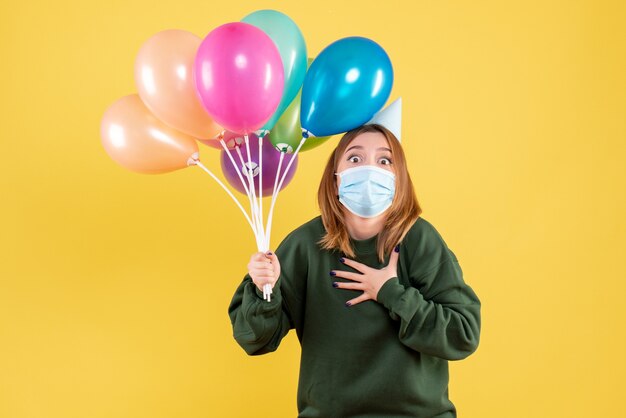 Front view young female in mask holding colorful balloons