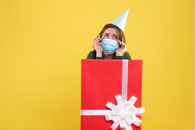 Front view young female in mask inside present box with sad face