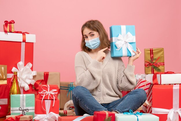 Front view young female in mask sitting around xmas presents