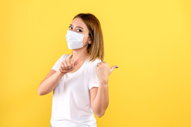 Front view of young female in mask on a yellow wall