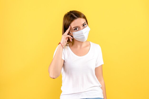 Front view of young female in mask on a yellow wall