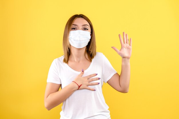 Front view of young female in mask on a yellow wall