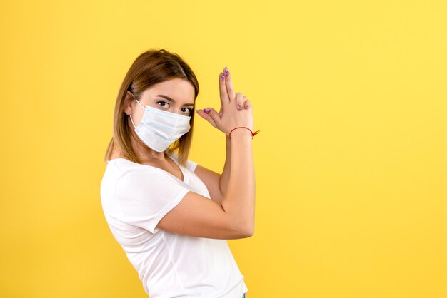 Front view of young female in mask on a yellow wall