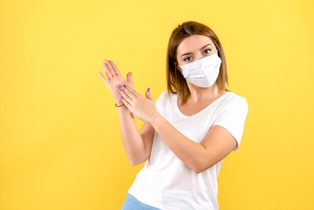 Front view of young female in mask on a yellow wall