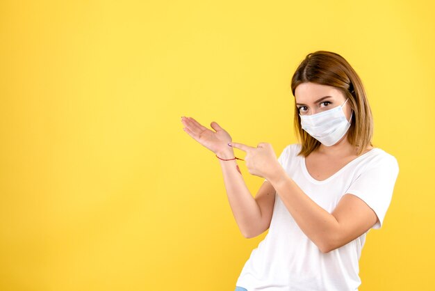 Vista frontale della giovane donna in maschera sulla parete gialla