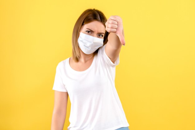 Front view of young female in mask on yellow wall