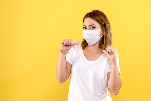 Front view of young female in mask on yellow wall