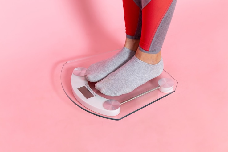 Free Photo front view young female measuring her weight on the pink wall exercise sport workout athlete waist beauty