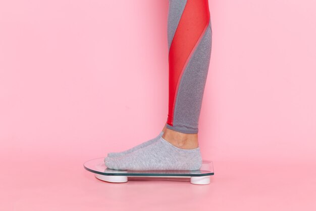 분홍색 벽 허리 스포츠 운동 운동 아름다움 슬림 선수에 그녀의 무게를 측정하는 전면보기 젊은 여성