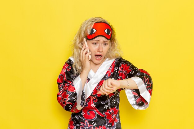 Free photo front view young female in night robe eye mask talking on the phone on yellow desk sleep night bed model