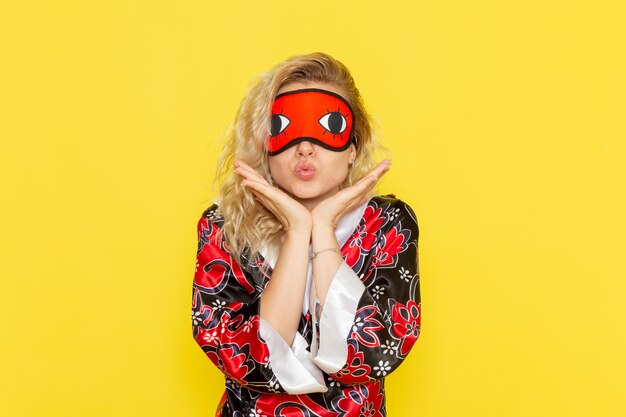 Front view young female in night robe and wearing eye mask preparing to sleep cute posing on yellow wall sleep female darkness color night