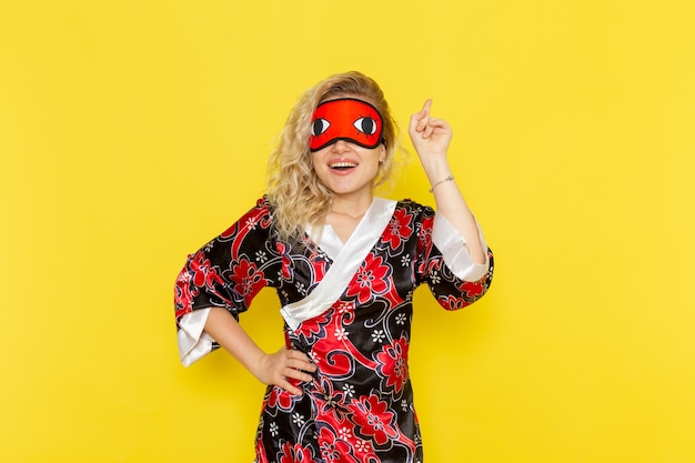 Front view young female in night robe and wearing eye mask preparing to sleep posing on yellow wall sleep female darkness color night