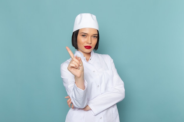 A front view young female nurse in white medical suit posing on the blue desk medicine hospital doctor