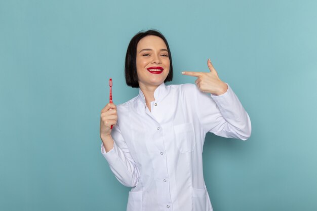 A front view young female nurse in white medical suit smiling on the blue desk medicine hospital doctor