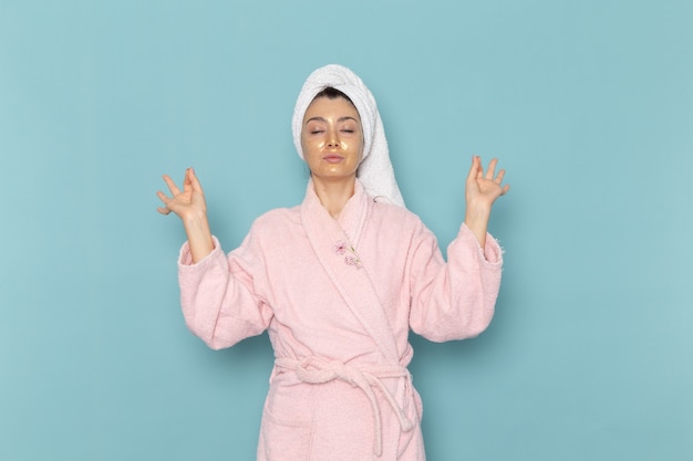 Front view young female in pink bathrobe after shower on the blue wall cleaning beauty clean water selfcare cream shower