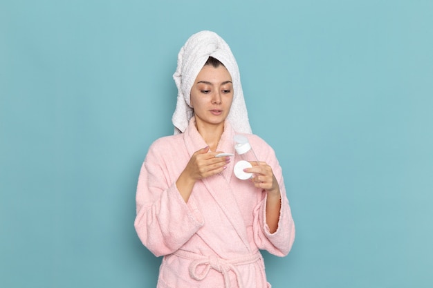 Free photo front view young female in pink bathrobe after shower on light blue wall cleaning beauty clean water selfcare cream shower