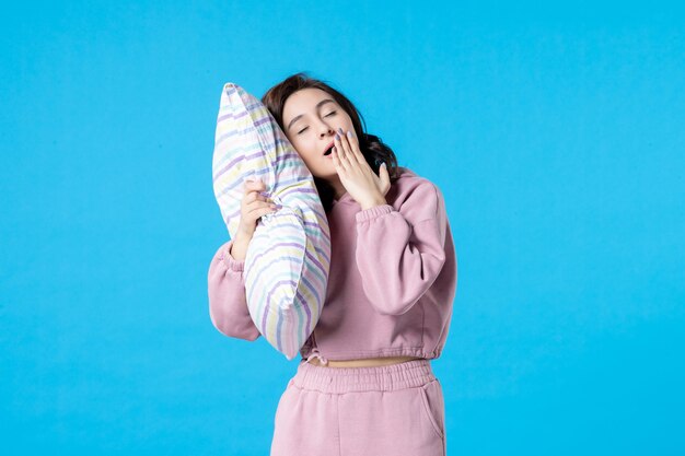 Front view young female in pink pajamas holding pillow on blue wall night color bed rest emotion dream woman sleep