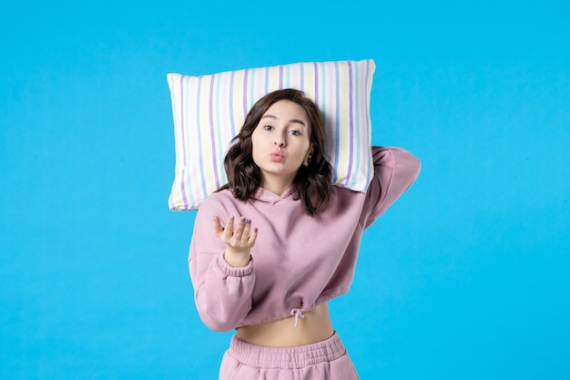 Front view young female in pink pajamas holding pillow on blue wall night color insomnia bed rest kiss dream woman party emotion sleep