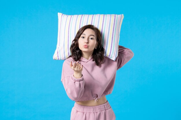 Front view young female in pink pajamas holding pillow on blue wall night color sleep bed rest dream woman insomnia party emotion kiss