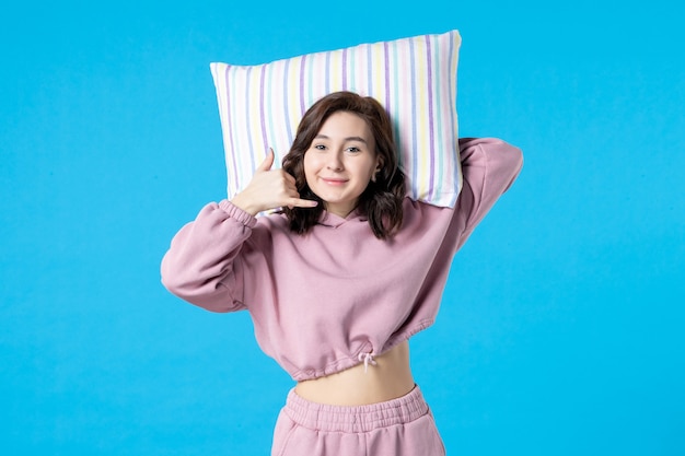 Front view young female in pink pajamas holding pillow on blue wall night color sleep bed rest dream woman insomnia party emotions