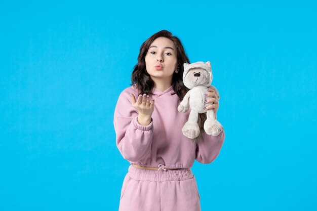 Front view young female in pink pajamas with little toy bear on blue color night sleep insomnia dream bed woman party rest kiss