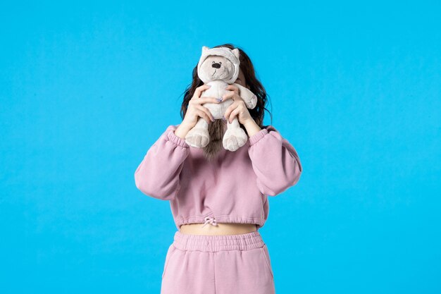Front view young female in pink pajamas with little toy bear on blue color night sleep insomnia dream bed woman party rest