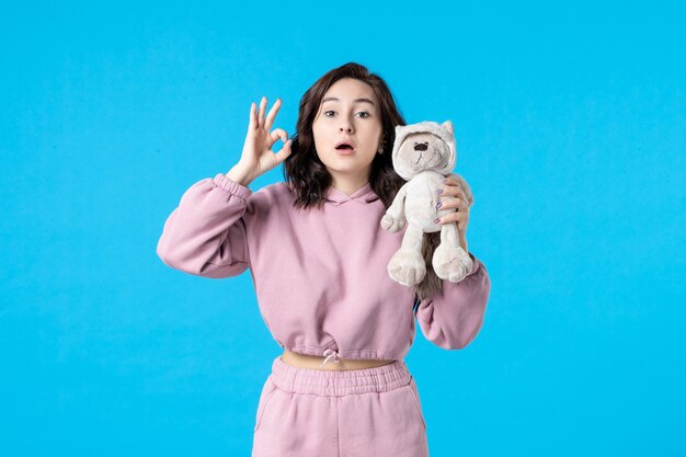 Front view young female in pink pajamas with little toy bear on blue color night sleep insomnia dream woman party rest