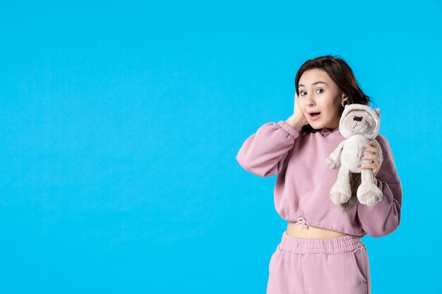 Front view young female in pink pajamas with little toy bear on blue dream 