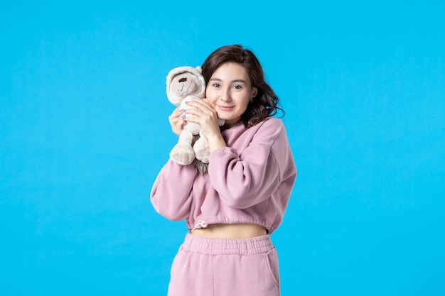 Front view young female in pink pajamas with little toy bear on blue night color insomnia dream rest bed woman party