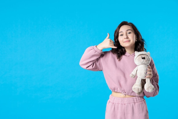 Free photo front view young female in pink pajamas with little toy bear on blue