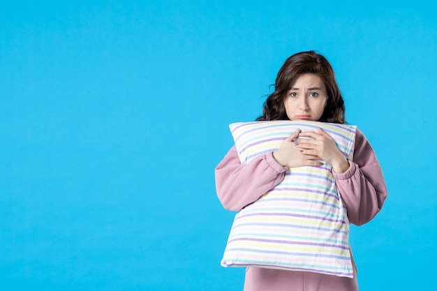 Front view young female in pink pajamas with pillow on blue