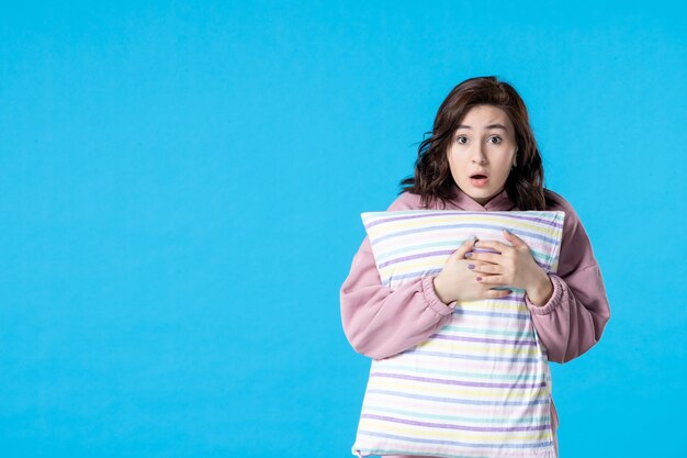 Front view young female in pink pajamas with pillow on blue