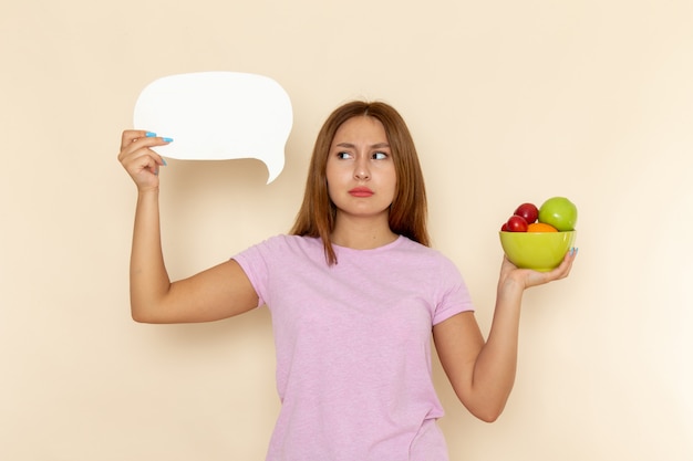 Front view young female in pink t-shirt and blue jeans holding plate with fruits white sign