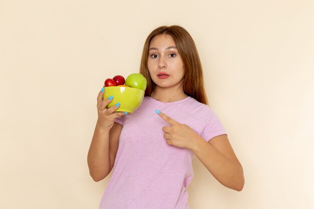 ピンクのtシャツとフルーツプレートを保持しているブルージーンズの正面の若い女性