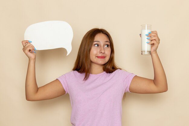 Front view young female in pink t-shirt and blue jeans holding white sign and milk on grey