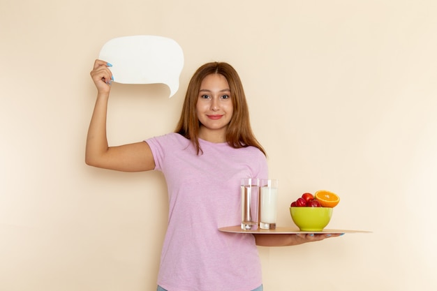 Front view young female in pink t-shirt holding tray fruits milk and water on grey