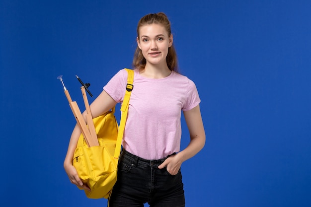 Free photo front view of young female in pink t-shirt wearing yellow backpack on the blue wall