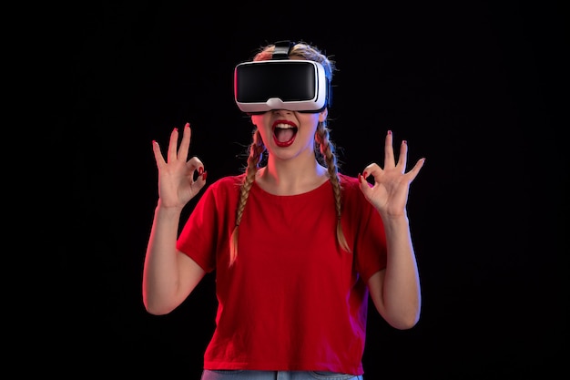 Вид спереди молодой женщины, играющей в виртуальную реальность на темной игровой ультразвуковой фантазии