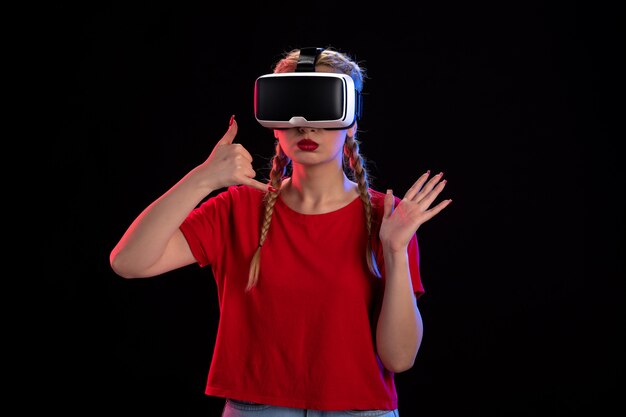 暗い壁で仮想現実をプレイする若い女性の正面図