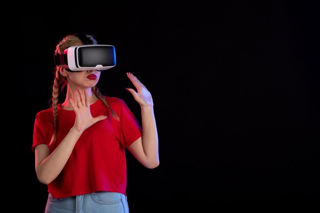 Front view of young female playing vr on a dark wall