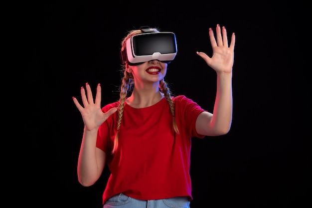 Front view of young female playing vr on a dark wall